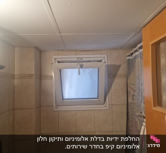 חלון קטן עם תריסים פתוחים בחדר אמבטיה